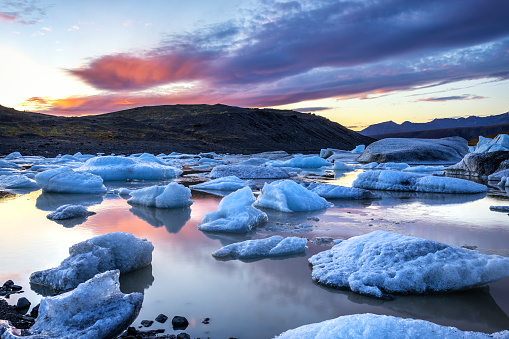 Sunset across the ice and mountains of Svinafellsjokul glacier lagoon at sunset, southern iceland. Part of the larger Vatnajokull glacier, the largest ice cap in iceland.