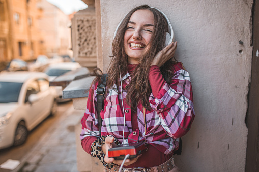 Young woman woman dressed in a plaid shirt enjoying listening to music on an old fashioned, retro Walkman
