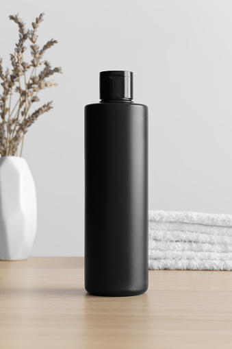 Black cosmetic lotion bottle mockup with a lavender and towels on the wooden table.