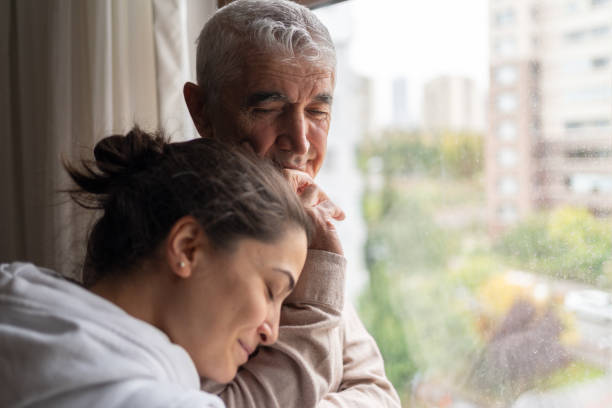 Daughter Embracing Her  Senior Father Daughter Embracing Her Contemplative Senior Father At Home piece of mind stock pictures, royalty-free photos & images