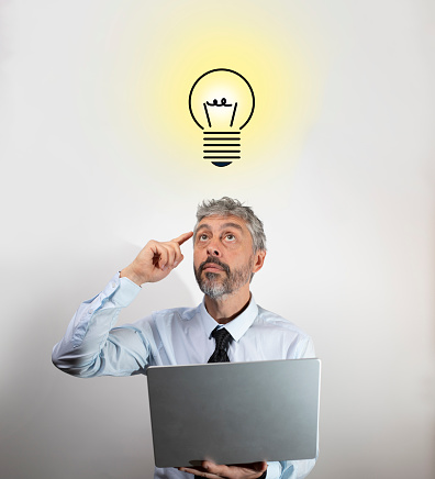 businessman working on a computer, thinking and finding an idea. A light bulb lights up above his head. Idea, imagination and genius concept