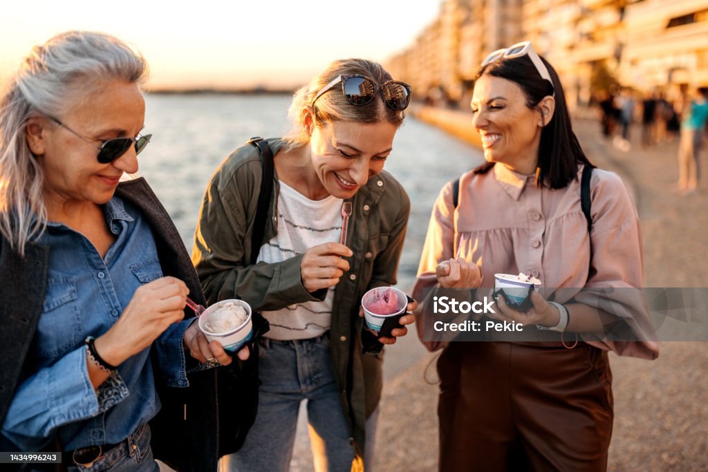 Ice cream time! Group of female friends having ice cream by the sea in the city Travel Stock Photo