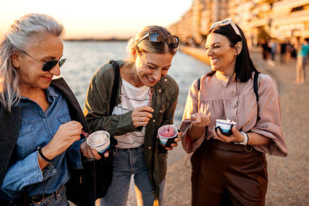 Ice cream time! Group of female friends having ice cream by the sea in the city female-friendship stock pictures, royalty-free photos & images