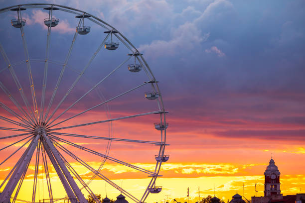 istock Ferris Wheel and illuminations in amusement park during scenic sunset with dramatic sky clouds and flying birds 1435001143