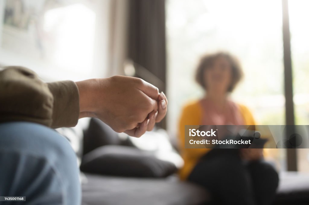 A teen girl in psychotherapy Close-up photo of a teenage girl's hands with fingers crossed nervously. She is in a therapy session with her psychotherapist. Psychotherapy Stock Photo