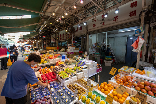 Hong Kong - October 20, 2022 : Shoppers at the Yau Ma Tei Fruit Market. It is a wholesale fruit market in Yau Ma Tei, Kowloon, Hong Kong. The market was founded in 1913.
