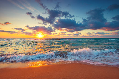Beautiful sunrise over the sea waves and beach on tropical island beach.