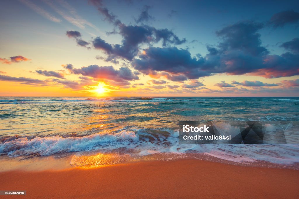 Beautiful sunrise over the sea waves and beach on tropical island beach Beautiful sunrise over the sea waves and beach on tropical island beach. Sunset Stock Photo