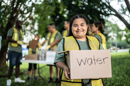 Portrait of a volunteer special needs young woman with a cardboard box at a public park