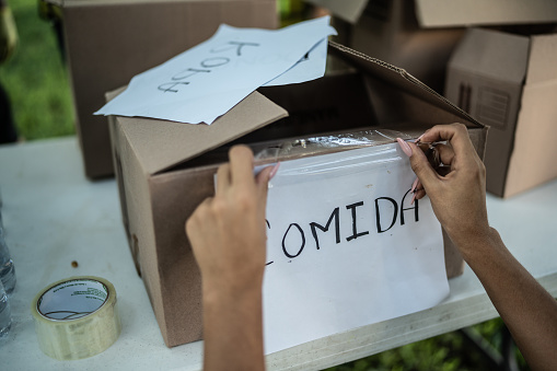 Close-up of a people sticking a paper on cardboard box with adhesive tape