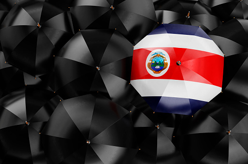 Umbrella with Costa Rican flag among black umbrellas, top view. 3D rendering