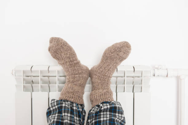 Man legs in wool socks warm on the radiator stock photo