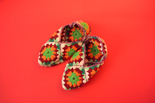 Cozy colorful crochet Slippers on Red Background