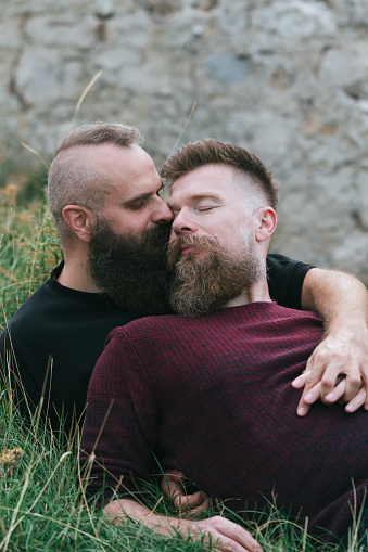 Pareja gay masculina hipsters besándose en la hierba photo