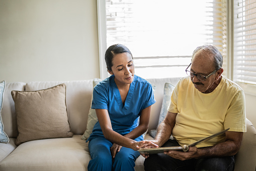 Senior man and nurse looking at photo album in the living room in a nursing home