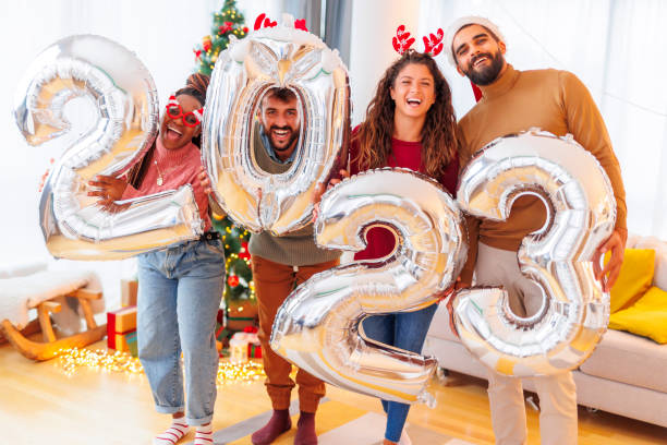 People holding giant balloons shaped as numbers 2023 while celebrating New Year stock photo