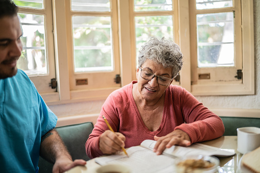 Senior woman playing with crosswords with nurse at home