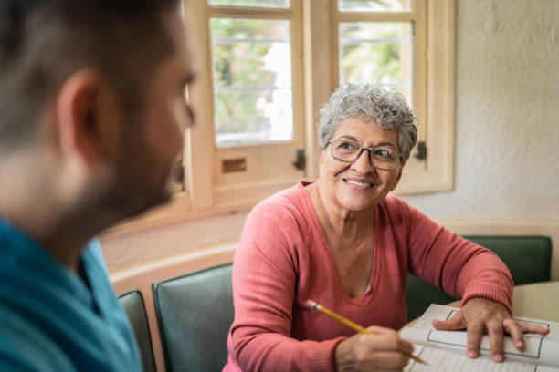 istock Senior woman talking while playing with crosswords with nurse at home 1435013345