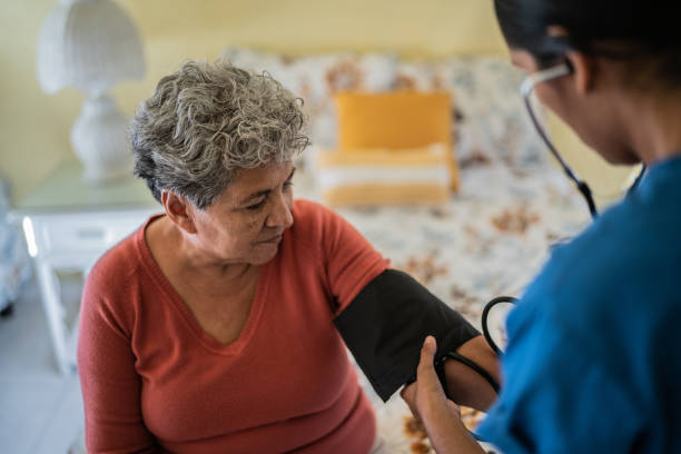 요양원의 침실에서 노인 여성의 압력을 측정하는 간호사 - nursing home nurse blood pressure gauge home caregiver 뉴스 사진 이미지