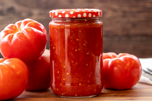 sauce tomate en conserve dans un bocal en verre sur fond de bois - garlic freshness isolated vegetarian food photos et images de collection