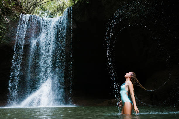 istock Woman have fun in natural pool under tropical waterfall 1435015448