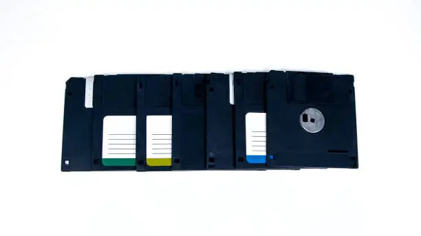 Photo of obsolete computer floppy disks with a flash drive on a white background,