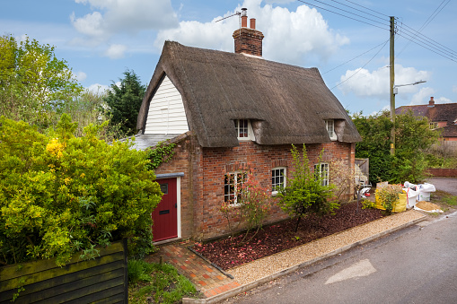 Rural thatched cottage and garden, Ashmore, North Dorset, England, UK. The tranquil picturesque ancient Roman village of Ashmore is the highest in elevation of any hamlet in Dorset and its various thatched, brick and flint construction buildings and properties of architectural interest are mainly clustered around the focal point of the village pond