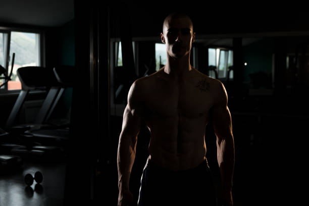 Silhouette Man Standing Strong In The Gym And Flexing Muscles