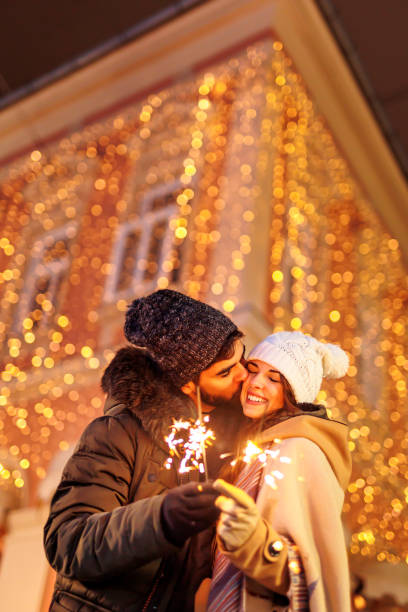 Couple holding sparklers while celebrating New Year outdoors stock photo