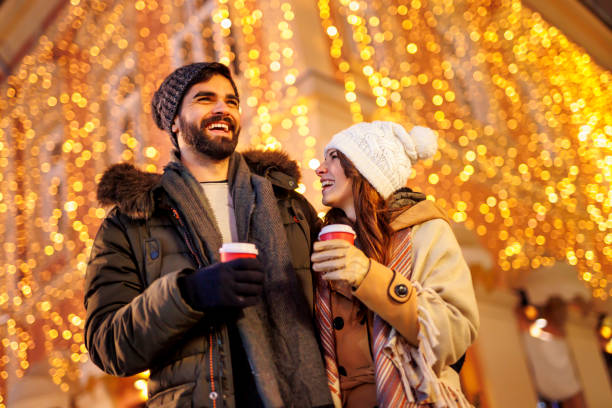 istock Couple drinking mulled wine and walking down decorated city streets while celebrating Christmas 1435024410