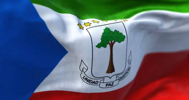 Close-up view of Equatorial Guinea national flag waving in the wind. The Republic of Equatorial Guinea is a Central African State. Fabric textured background. Selective focus