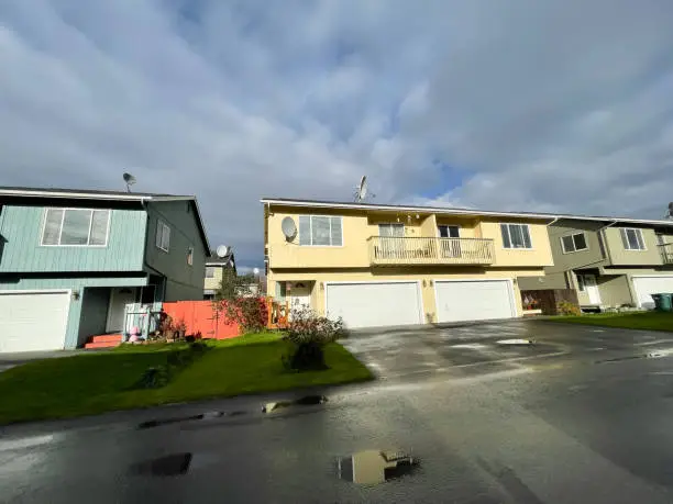 Typical two story duplex houses has two units in same building, share a common wall in Anchorage, Alaska. Multi-family home arranged side by side with large concrete pathway and curb appeal