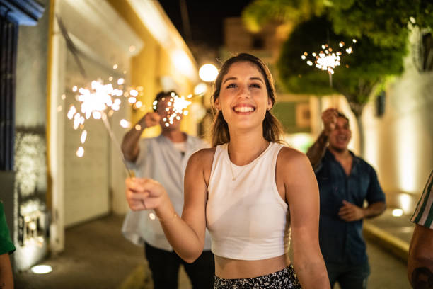 Young woman playing with sparklers on the street at night stock photo