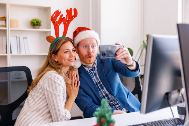 istock Business colleagues having fun taking selfies while celebrating Christmas at the office 1435029268