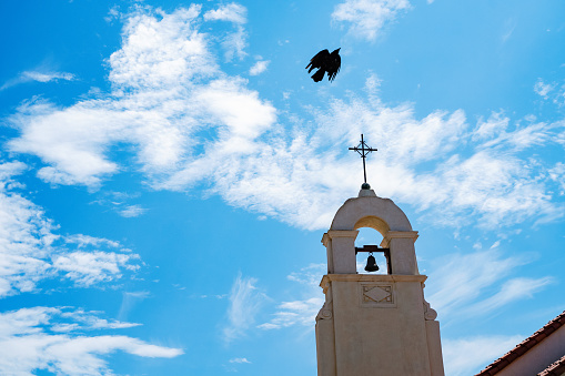 La Jolla Spanish mission style church bell tower with raven in San diego California. Religious symbolism of mexican culture and gothic illustration