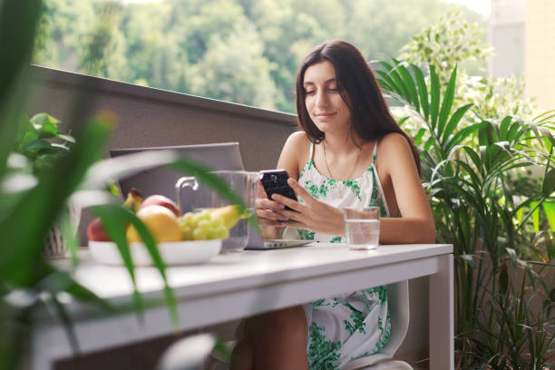 istock Woman sitting on the balcony and using her smartphone 1435034052