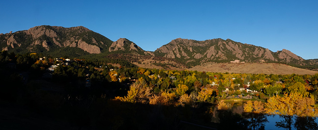 Panoramic view of a south Boulder, Colorado neighborhood at dawn with the Flatirons and mountains behind. Autumn foliage.
