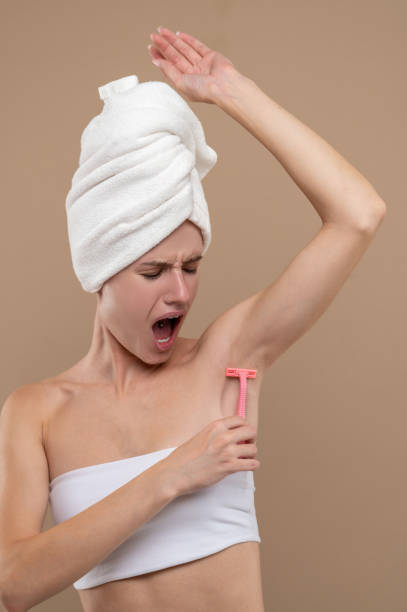 istock Young woman shaving underarms area 1435034615