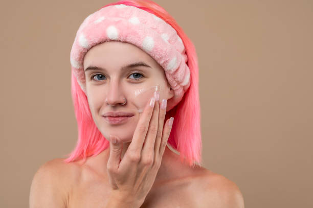 istock Cute pink-haired girl putting cream on her face 1435034643