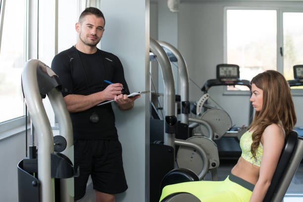 istock Personal Trainer Takes Notes While Woman Exercising Legs 1435035338