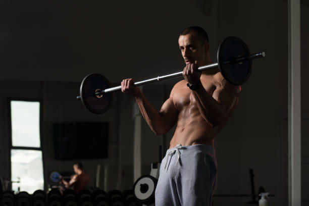 istock Man In The Gym Exercising Biceps With Barbell 1435038117