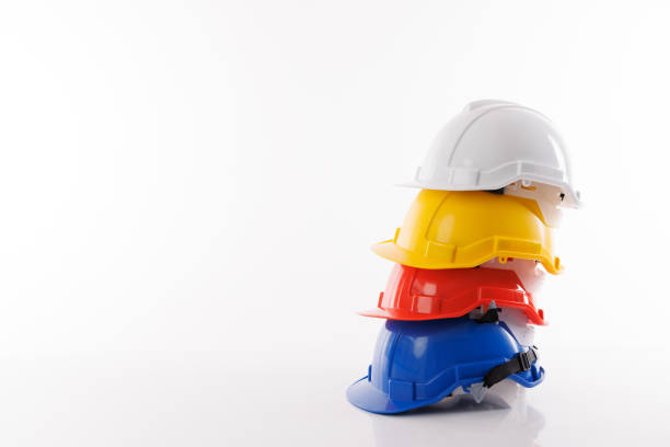 stacked blue, red, yellow and white industry safety helmet on white table and white background.