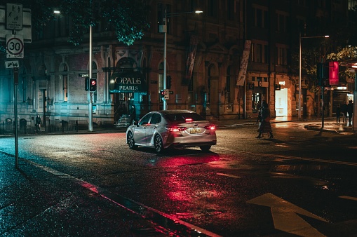sydney, Australia – October 08, 2022: A car on a wet asphalt road in Sydney, Australia at night