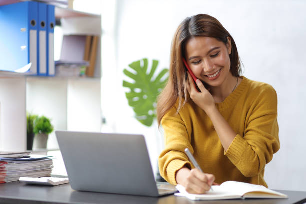 istock Woman using mobile phone to talk to coworker while working in home office. Work from home concept. 1435045794