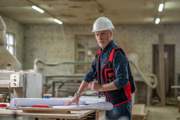 istock Man in protective helmet working in a workshop with drawings 1435046937