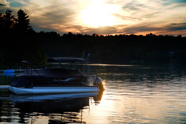 Pontoon boat on lake with a evening sunset A picture of a pontoon boat on lake with a evening sunset pontoon boat stock pictures, royalty-free photos & images