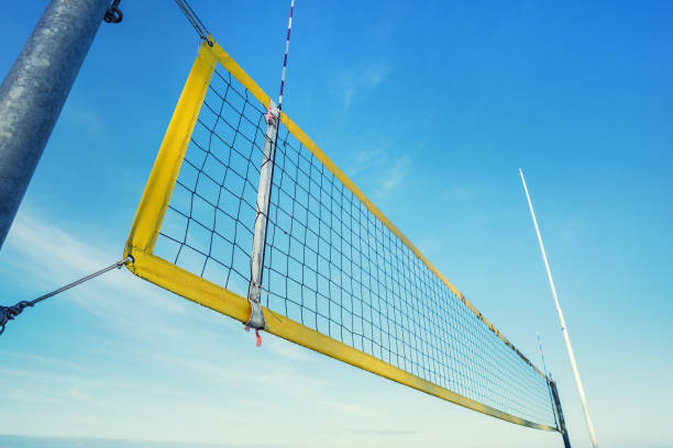 rete da beach volley con telaio giallo fissata su palo metallico in riva al mare - volleyball net leisure activity beach foto e immagini stock