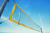 Beach volley net with yellow frame fixed on metal pole on seashore