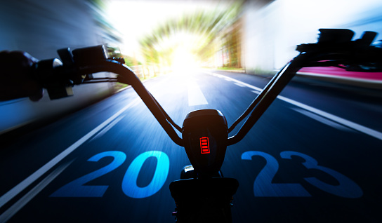 Abstract blur riding electric bicycle and new year number 2023 on road