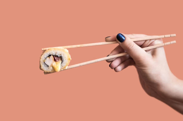 istock A hand holds a fried sushi roll with cheese with wooden sticks 1435054101